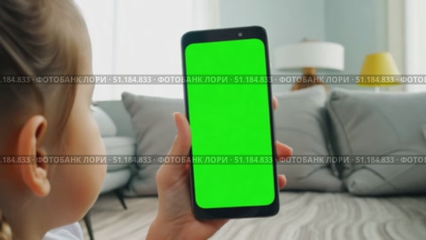 A young girl interacts with a blank smartphone screen in a bright and inviting living room setting. Стоковое AI-видео, аниматор Данила Большаков / Фотобанк Лори