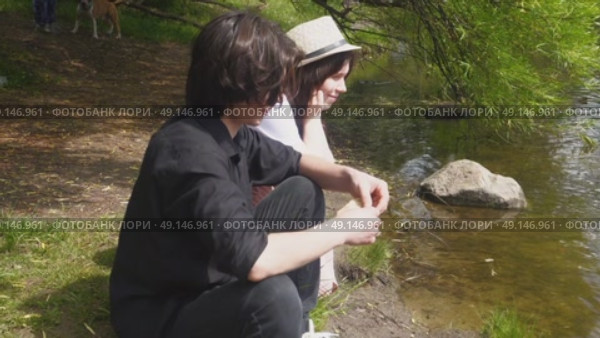 A young happy couple feeds ducks on the shore of a pond in a summer park. Стоковое видео, видеограф Ярославский Максим / Фотобанк Лори