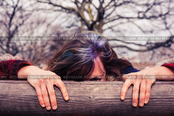 A young woman is hiding behind a wooden beam in the park. Стоковое фото, агентство Ingram Publishing / Фотобанк Лори