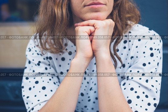 A young woman is sitting with her head resting on her hands and daydreaming. Стоковое фото, агентство Ingram Publishing / Фотобанк Лори
