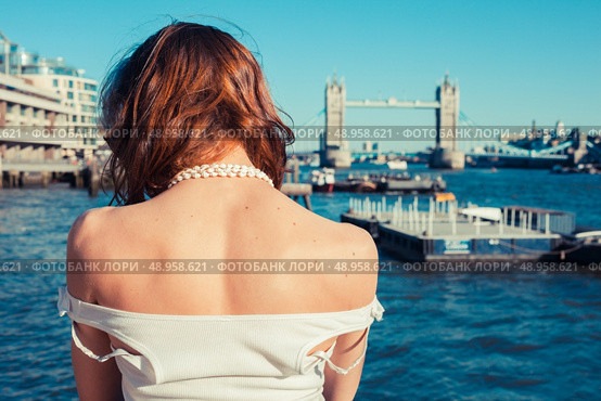 A young woman is tanning her back on a sunny day and looking at the river Thames in London, England. Стоковое фото, агентство Ingram Publishing / Фотобанк Лори