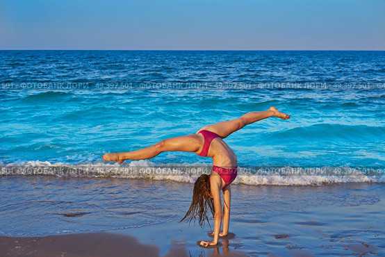 acrobatic gymnastics bikini girl in a beach blue shore at summer. Стоковое фото, агентство Ingram Publishing / Фотобанк Лори