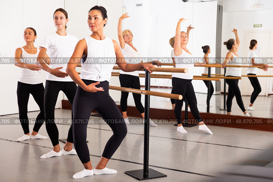 Active dancing women perform demi plie near the ballet barre, standing in a ballet stance. Стоковое фото, фотограф Яков Филимонов / Фотобанк Лори