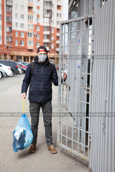Adult Caucasian man taking out the trush during covid-19 pandemic, it is allowed without any permission. Стоковое фото, фотограф Кекяляйнен Андрей / Фотобанк Лори