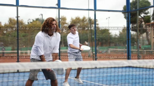 adult man paddle tennis player during friendly doubles pair match with guy partner at outdoors court. Стоковое видео, видеограф Яков Филимонов / Фотобанк Лори