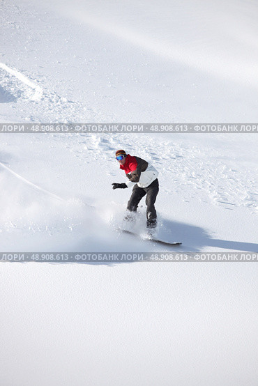 Adventurous man snowboarding down hill. Стоковое фото, агентство Ingram Publishing / Фотобанк Лори