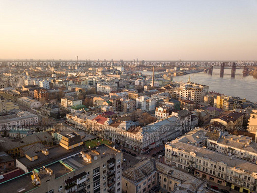 Aerial panoramic view from the drone to the oldest district of Kiev - Podol, Sahaidachnoho street, the Podolsky bridge, Havana bridge, old buildings and other historical places.. The panoramic bird’s eye view from drone to the central historical part of the city Kiev - the Podol district, the Dnieper River in Kiev, Ukraine at summer sunset. Стоковое фото, агентство Ingram Publishing / Фотобанк Лори