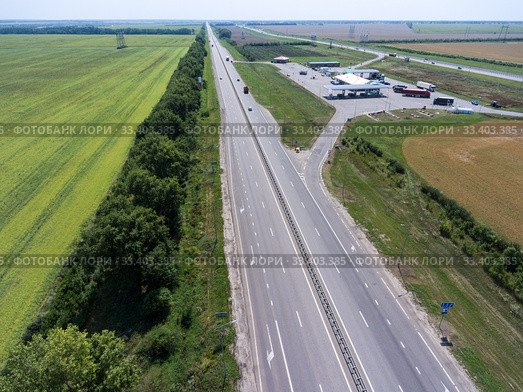 Aerial view at long straight highway with petrol station between two routes, plain terrain. Стоковое фото, фотограф Кекяляйнен Андрей / Фотобанк Лори