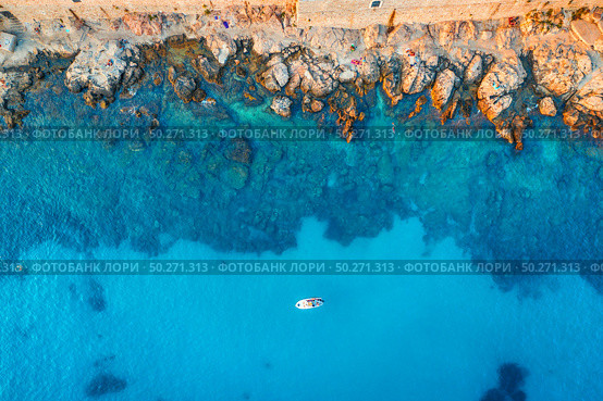 Aerial view of beach with stones and rocks, alone boat in adriatic sea at sunset in summer. Top view of yacht in transparent blue water. Travel in Croatia. Nature background. Landscape with ocean. Стоковое фото, агентство Ingram Publishing / Фотобанк Лори