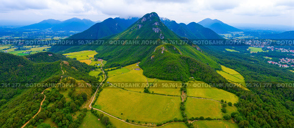 Aerial view of spectacular mountain range with green fields and forest in rural valley, amazing nature landscape for travel inspiration. Стоковое AI-изображение, AI-художник Павел Муравьев / Фотобанк Лори