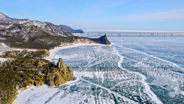 Aerial view of the frozen Lake Baikal, beautiful mountains, ice with cracks. Cape Kolokolny, Sandy Bay in winter.  Вид с высоты птичьего полета на замерзшее озеро Байкал, красивые горы, лед с трещинами. Мыс Колокольный, Песчаная бухта зимой. Стоковое видео, видеограф Виктория Тельминова / Фотобанк Лори