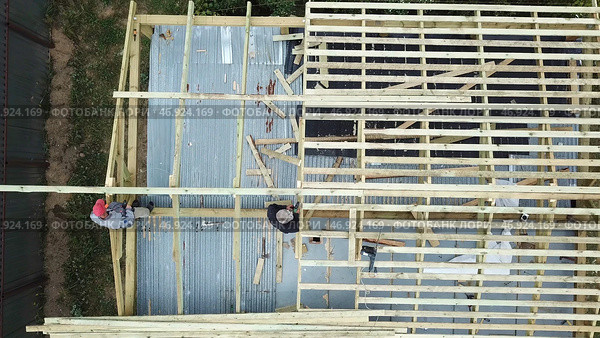 Aerial view of two senior men building a wooden frame house in the summer on their own location. Стоковое фото, фотограф David Kashakhi / Фотобанк Лори