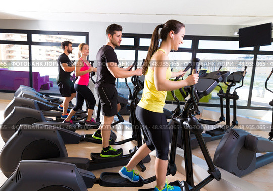 Aerobics elliptical walker trainer group at fitness gym workout. Стоковое фото, агентство Ingram Publishing / Фотобанк Лори