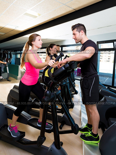Aerobics elliptical walker trainer personal trainer man at fitness gym workout. Стоковое фото, агентство Ingram Publishing / Фотобанк Лори