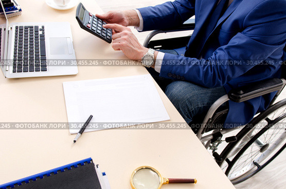 Aged employee in wheelchair working in the office. Стоковое фото, фотограф Elnur / Фотобанк Лори