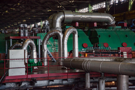 Aksu, Pavlodar region, Kazakhstan - May 29, 2012: Aksu steam power station workshop. Green electric machine, steam turbine and generator. Pipes with thermal insulation and shiny metal cover. Редакционное фото, фотограф Alexey Rezvykh / Фотобанк Лори