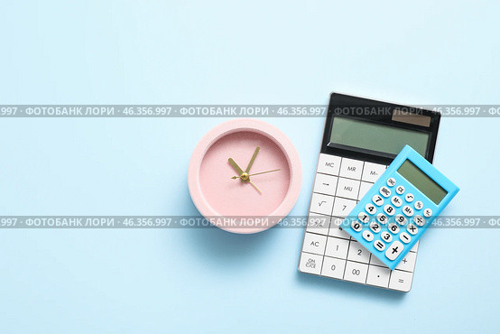 Alarm clock with calculators on color background. Стоковое фото, фотограф Pixel_shot / Фотобанк Лори