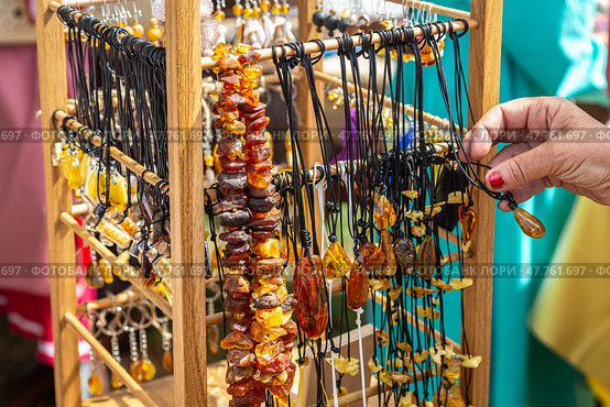 Amber beads in a street shop. The hand in the frame selects amber beads. Souvenir the Baltic Sea. Стоковое фото, фотограф Ольга Сейфутдинова / Фотобанк Лори