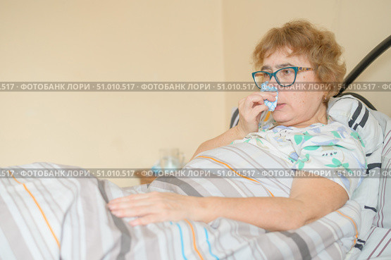An elderly woman suffers from the flu and runny nose. The pensioner blows her nose in the nasal raft. Стоковое фото, фотограф Михаил Решетников / Фотобанк Лори
