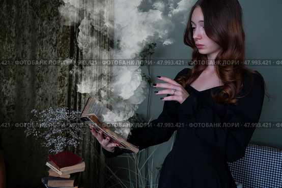 An Enchanting Sorceress is deeply engrossed in reading a Spellbook surrounded by swirling, Mystical Smoke. Стоковое фото, фотограф Anastasy Yarmolovich / Фотобанк Лори