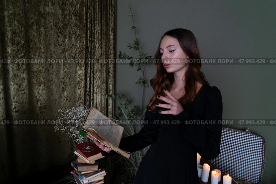 An Enchanting Sorceress is deeply engrossed in reading a Spellbook surrounded by swirling, Mystical Smoke. Стоковое фото, фотограф Anastasy Yarmolovich / Фотобанк Лори