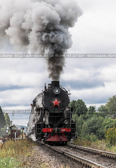 An old Soviet steam locomotive of the L series. The Ruskeala Express retro train is on its way to the mountain park. Thick smoke is coming from the chimney. Russia, Republic of Karelia, Sortavala, August 11, 2025. Редакционное фото, фотограф Photojuli / Фотобанк Лори