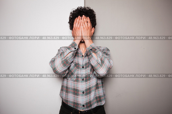 An upset young man is standing against a green and white background. Стоковое фото, агентство Ingram Publishing / Фотобанк Лори