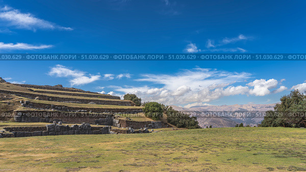 Ancient ruins of a Magnificent Inca Fortress Sacsayhuaman. Multi-tiered terraces and walls made of Ashlar polygonal masonry technique. A square with green grass in the foreground. Peru. Cusco. Стоковое фото, фотограф Вера Ивановна Кубарева / Фотобанк Лори