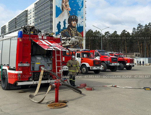 ANGARSK, IRKUTSK REGION, RUSSIA - April 08, 2025: Firefighters connect fire hose to street hydrant to extinguish fire. Red fire trucks lined up on square. Preventive training of firefighters. EMERCOM. Редакционное фото, фотограф Виктория Катьянова / Фотобанк Лори