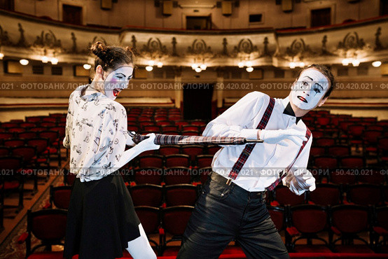 angry female mime artist hitting male mime with umbrella auditorium. Стоковое фото, агентство Ingram Publishing / Фотобанк Лори
