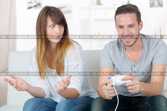 annoyed girlfriend waiting for boyfriend to stop playing video-games. Стоковое фото, агентство Ingram Publishing / Фотобанк Лори