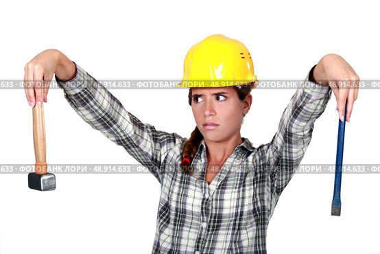 Apprehensive tradeswoman holding a hammer and chisel. Стоковое фото, агентство Ingram Publishing / Фотобанк Лори