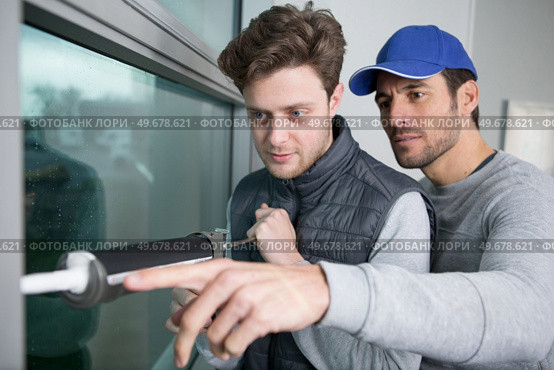 apprentice being advised how to apply caulk to window. Стоковое фото, агентство Ingram Publishing / Фотобанк Лори