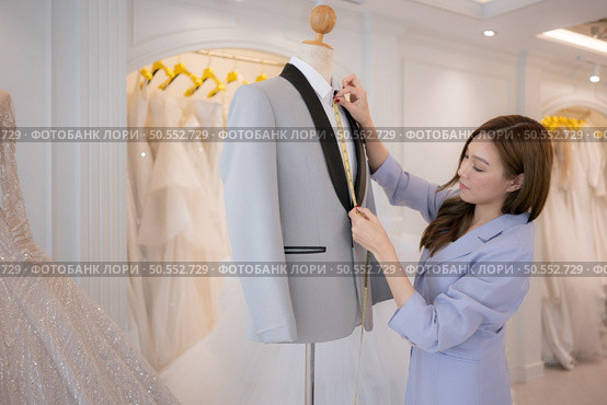 Asian fashion designers make sure the groom’s outfit is absolutely accurate and ready for the bride and groom to try on. Стоковое фото, агентство Ingram Publishing / Фотобанк Лори