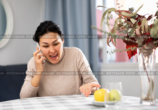 Asian woman swears at someone while talking on a mobile phone. Стоковое фото, фотограф Яков Филимонов / Фотобанк Лори