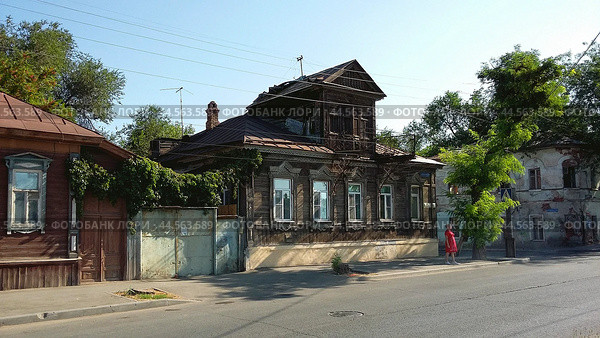 Астрахань. Старинный дом с мезонином ( памятник архитектуры ) на Варвациевской набережной, 107 ( Набережная 1 Мая ). По стилю дом относится к первой половине 19 века, и до недавнего времени был, по сравнению со своими соседями в очень хорошем состоянии. По непонятным причинам вскрыта из нутри  кровля мезонина ( левая его  часть ). На дворе осень, скоро дожди, снег...  Перекрытия в старинных домах ДЕРЕВЯННЫЕ. Какаих нибудь 3-4 года, и памятник архитектуры признают аварийным с вытекающими последствиями, и  таких примеров на моей памяти уже не мало. (2024 год). Редакционное фото, фотограф Павел Просянов / Фотобанк Лори