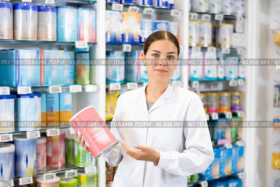 At pharmacy, apothecary holds jar of baby formula in hands and talks about properties of product. Стоковое фото, фотограф Яков Филимонов / Фотобанк Лори