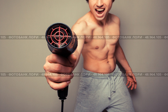 Athletic young man is holding a hair dryer and messing around with it. Стоковое фото, агентство Ingram Publishing / Фотобанк Лори