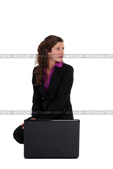 attractive young businesswoman crouching with laptop. Стоковое фото, агентство Ingram Publishing / Фотобанк Лори