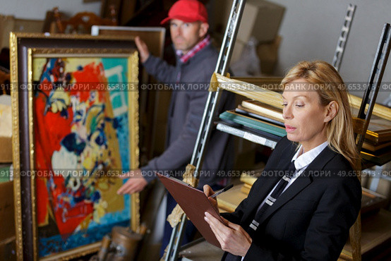 auctioneer and assistant rchecking auction goods. Стоковое фото, агентство Ingram Publishing / Фотобанк Лори