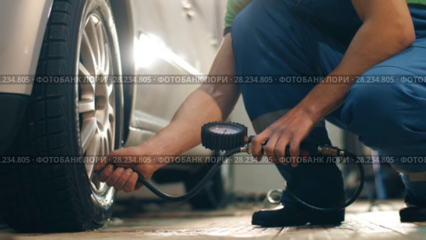 Auto mechanic pumps wheel of a car. Стоковое видео, видеограф Илья Шаматура / Фотобанк Лори