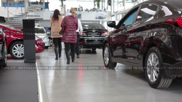 Автосалон по продаже новых автомобилей. Продавец с покупателями ходят среди машин (2015 год). Редакционное видео, видеограф Кекяляйнен Андрей / Фотобанк Лори