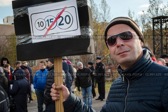 Автовладелец держит плакат на митинге против введения зоны платных парковок в городе Москве в парке спального района (2015 год). Редакционное фото, фотограф Николай Винокуров / Фотобанк Лори