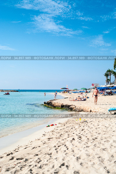 Ayia Napa, Cyprus-circa Sep, 2010: White sand and turquoise sea water are on the Nissi beach. It is a popular sandy beach in the resort of Ayia Napa. The beach have small islet of Nissi. Редакционное фото, фотограф Кекяляйнен Андрей / Фотобанк Лори