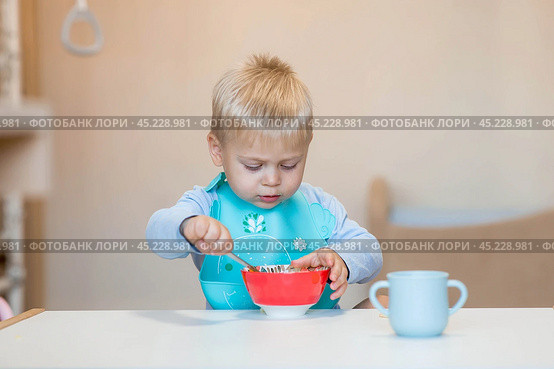 Baby food. Eating. Feeding the baby. A cute kid eats on his own with a spoon. Healthy eating. Family and children. Стоковое фото, фотограф Photojuli / Фотобанк Лори
