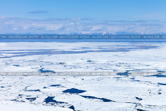 Baikal Lake in May. View from Olkhon Island to the ice drift in the Small Sea. Spring  landscape with mountains in the distance. Natural spring ice floating background. Change seasons. Spring travels. Стоковое фото, фотограф Виктория Катьянова / Фотобанк Лори