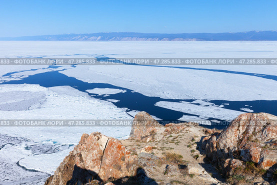 Baikal Lake in spring. View from rocky Cape Sagan-Khushun of Olkhon Island to ice destruction and ice drift on Small Sea. Beautiful spring landscape with stones covered red lichens. Natural background. Стоковое фото, фотограф Виктория Катьянова / Фотобанк Лори