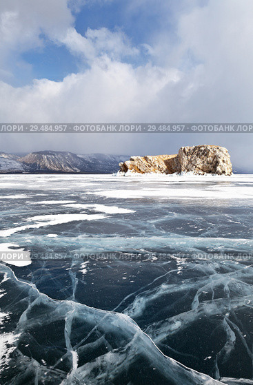Baikal Lake in winter. Strait Small Sea (Maloe More). Beautiful smooth ice with cracks near the stone island of Borga-Dagan on the background of cumulus clouds. Стоковое фото, фотограф Виктория Катьянова / Фотобанк Лори