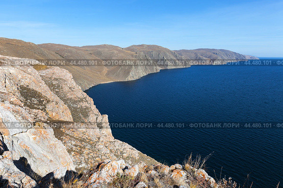 Baikal Lake on Autumn sunny windy day. View from coastal rock to treeless rocky shore of western coast of lake on October. Traveling and hiking along Tazheran steppe and Baikal lake shore. Стоковое фото, фотограф Виктория Катьянова / Фотобанк Лори