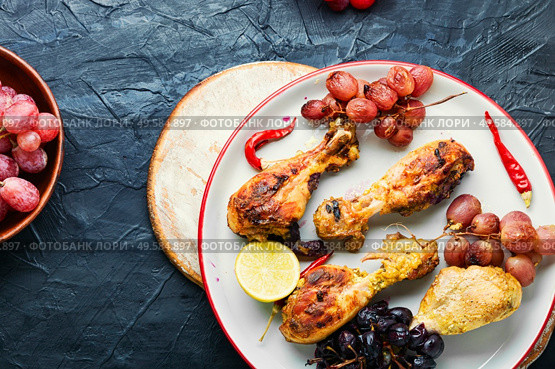 Baked chicken legs with grapes.Roasted chicken legs on plate. Barbecued chicken drumsticks. Стоковое фото, агентство Ingram Publishing / Фотобанк Лори